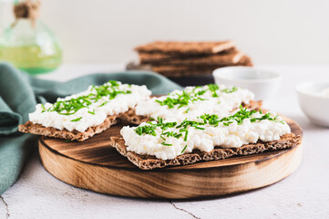 Homemade crispy rye toasts with ricotta and herbs on a board