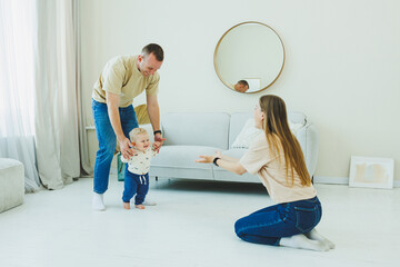 Young parents are playing with their little 10-month-old son. Mom and dad are playing with their...