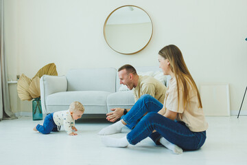 Young parents are playing with their little 10-month-old son. Mom and dad are playing with their...