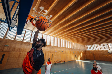 Portrait of an african man with short dreadlocks dunking the ball into hoop