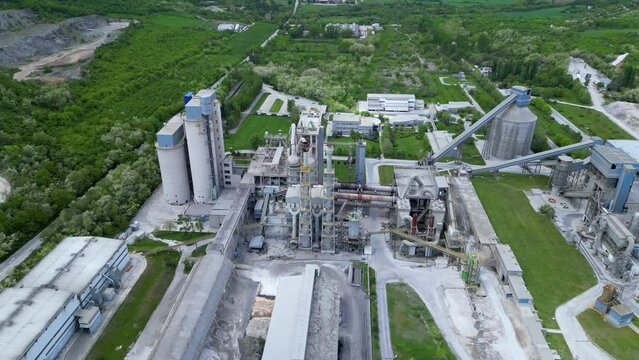 High angle aerial footage of a cement factory in a mountainous area. Cement mill and concrete production from limestone in a forrested area in Bulgaria. Drone shot of industrial calcium sulphate.
