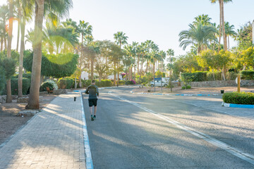 Man jogging on the street with palm trees near to the sea.