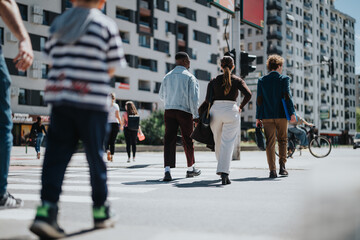 A diverse group of business professionals engaging in a walking meeting across a city street, exemplifying teamwork and cooperation in an outdoor urban setting.