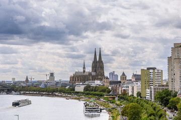 Fototapeta premium Cologne with a Rhine river running through it and a large cathedral in the background