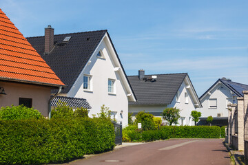City street of single-family modern houses Germany against blue sky. German suburban small town...