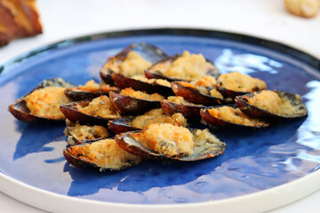 Plate of mussels au gratin. Mussels covered in wine and stuffed with breadcrumbs and Parmesan, finally grating them in the oven