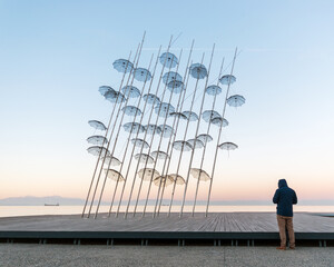 A man stands close to the Umbrellas installation at the New Waterfront of Thessaloniki during...