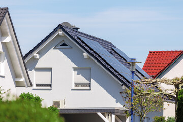 City street  single-family modern houses  solar photovoltaic panels roof Germany against blue sky. German suburban small town residential area  row eco sustainable life building neighborhood suburb