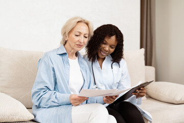 Senior Woman Consulting With Doctor At Home, Discussing Medical Reports, Healthcare Support, Elderly Patient And Female Physician, Healthcare Concept