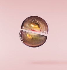 Fresh organic Blue Grape falling in the air isolated on pink background. Food levitation or zero gravity conception.