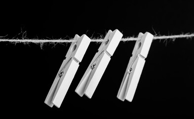 wooden clothespins on a jute rope on a black background