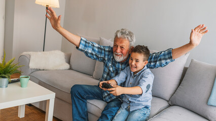 Grandfather and grandson playing video game with console, happy time together. Grandfather with his...