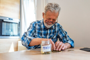 Senior man holding a glass jam jar full of banknotes, saving for a Pension. Senior man  saving...