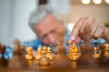 Senior man with contemplating chess move. Hand of an experienced chess players. Hand of man playing...