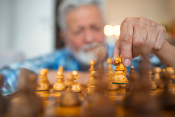 Playing wooden chess pieces. A man's hand takes a white chess knight and prepares to make his move....