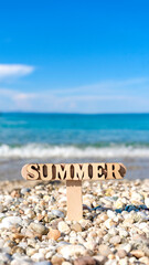 Wooden summer sign on the beautiful rocky beach