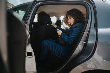 Businesspeople sitting in a car while preparing for a meeting. Professional attire, focused demeanor, and intensity suggest a corporate setting.