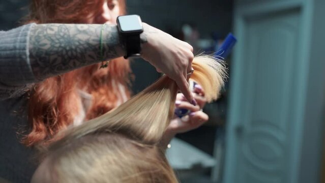 a beautiful young girl with short hair and a bob haircut is doing a procedure in a beauty salon. Hair master doing coloring and tone to client's hair close-up
