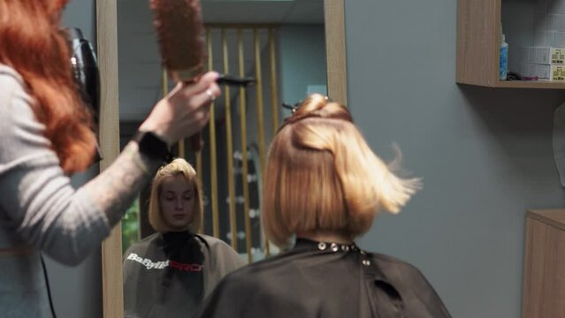 a beautiful young girl with short hair and a bob haircut is doing a procedure in a beauty salon. Hair master doing coloring and tone to client's hair close-up