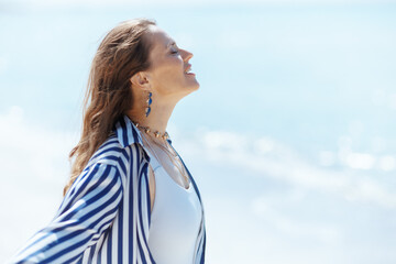 smiling stylish woman on beach enjoying peace of mind
