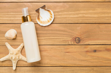 Sunscreen lotion with summer decor on wooden background, top view