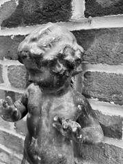 Black and white photograph featuring a statue resembling a cherub or child-like figure.