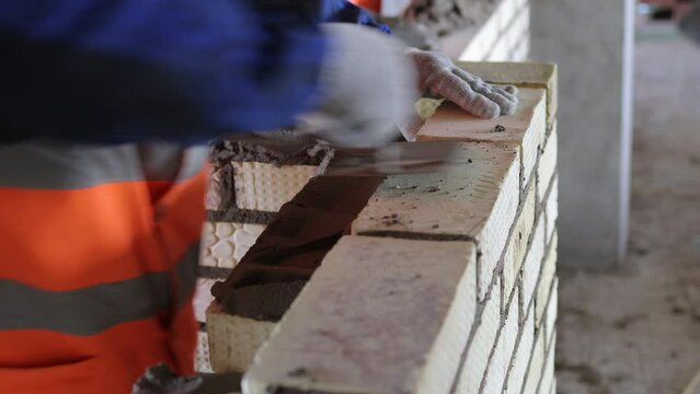 Construction worker is expertly laying bricks at the construction site with precision and skill