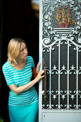 A woman stands expectantly in the doorway of a traditional Portuguese home, looking out with...