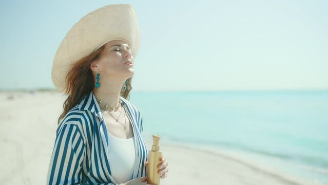 smiling elegant female on the seacoast with sunscreen.
