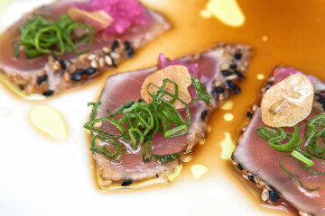 Tuna sashimi, sliced ​​tuna fillet with black sesame, olive oil and teriyaki sauce, food close up view