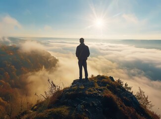 A man stands on the edge of a cliff, overlooking a misty valley at sunrise.