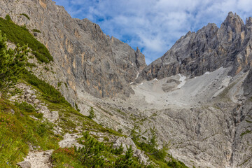 Dolomiti Alps beautiful mountain landscape. Rocky tower alpine summits in the Dolomites. Summer mountain scenic view on the hiking trekking path in the green mountain valley and blue sky with clouds