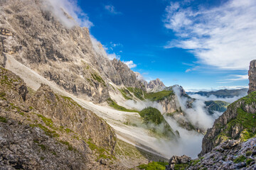 Dolomiti Alps beautiful mountain landscape. Rocky tower alpine summits in the Dolomites. Summer mountain scenic view on the hiking trekking path in the green mountain valley and blue sky with clouds