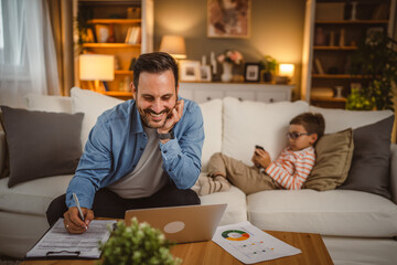 Father work from home write at the document with son at background