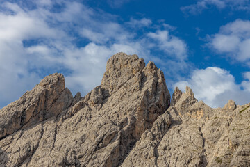 Dolomiti Alps beautiful mountain landscape. Rocky tower alpine summits in the Dolomites. Summer mountain scenic view on the hiking trekking path in the green mountain valley and blue sky with clouds