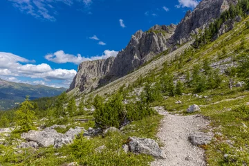 Dolomiti Alps beautiful mountain landscape. Rocky tower alpine summits in the Dolomites. Summer mountain scenic view on the hiking trekking path in the green mountain valley and blue sky with clouds