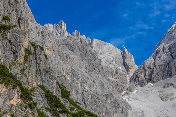 Dolomiti Alps beautiful mountain landscape. Rocky tower alpine summits in the Dolomites. Summer mountain scenic view on the hiking trekking path in the green mountain valley and blue sky with clouds