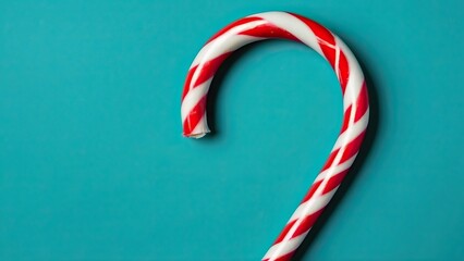 Fototapeta premium Red and white candy cane on a teal background, festive and minimalistic design