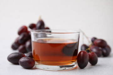 Wine vinegar in glass bowl and grapes on light grey table