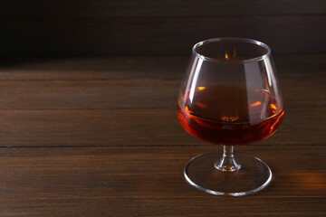 Delicious liqueur in glass on wooden table. Space for text