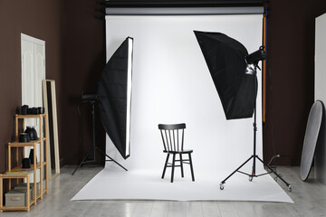 White photo background, chair and professional lighting equipment in studio