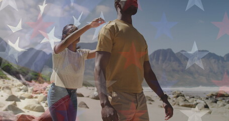 Image of american flag over smiling diverse couple carrying in mountains