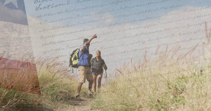 Image of american flag over diverse couple hiking in mountains - Powered by Adobe