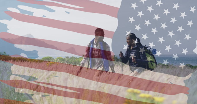 Image of american flag over smiling diverse couple hiking in mountains - Powered by Adobe