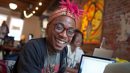 Obraz premium A joyful person with vibrant pink hair and tattoos, wearing glasses and working on a laptop in a brightly decorated, cozy workspace