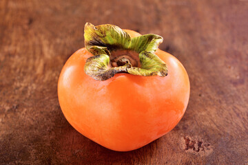 Delicious ripe persimmon fruit on wooden table.  