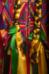Fototapeta premium A person wearing a colorful dress with two long braided ribbons