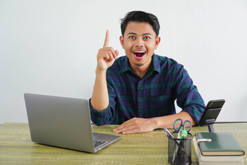 Joyful young asian man sit work at wooden desk with pc laptop. Achievement business career...