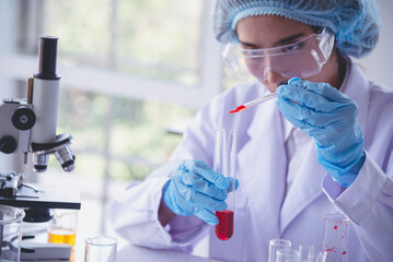 Scientist woman holding chemical test glass tube testing science laboratory. Lab technician holding red drop to glass tube diagnosis blood sample. Asian woman scientist working test medical chemistry