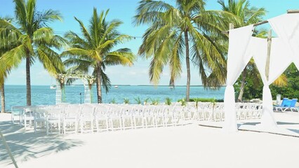 Slow wide shot of wedding venue by the beach on a sunny day with peace and tranquility outdoor seating sandy beach engagement seating with tables